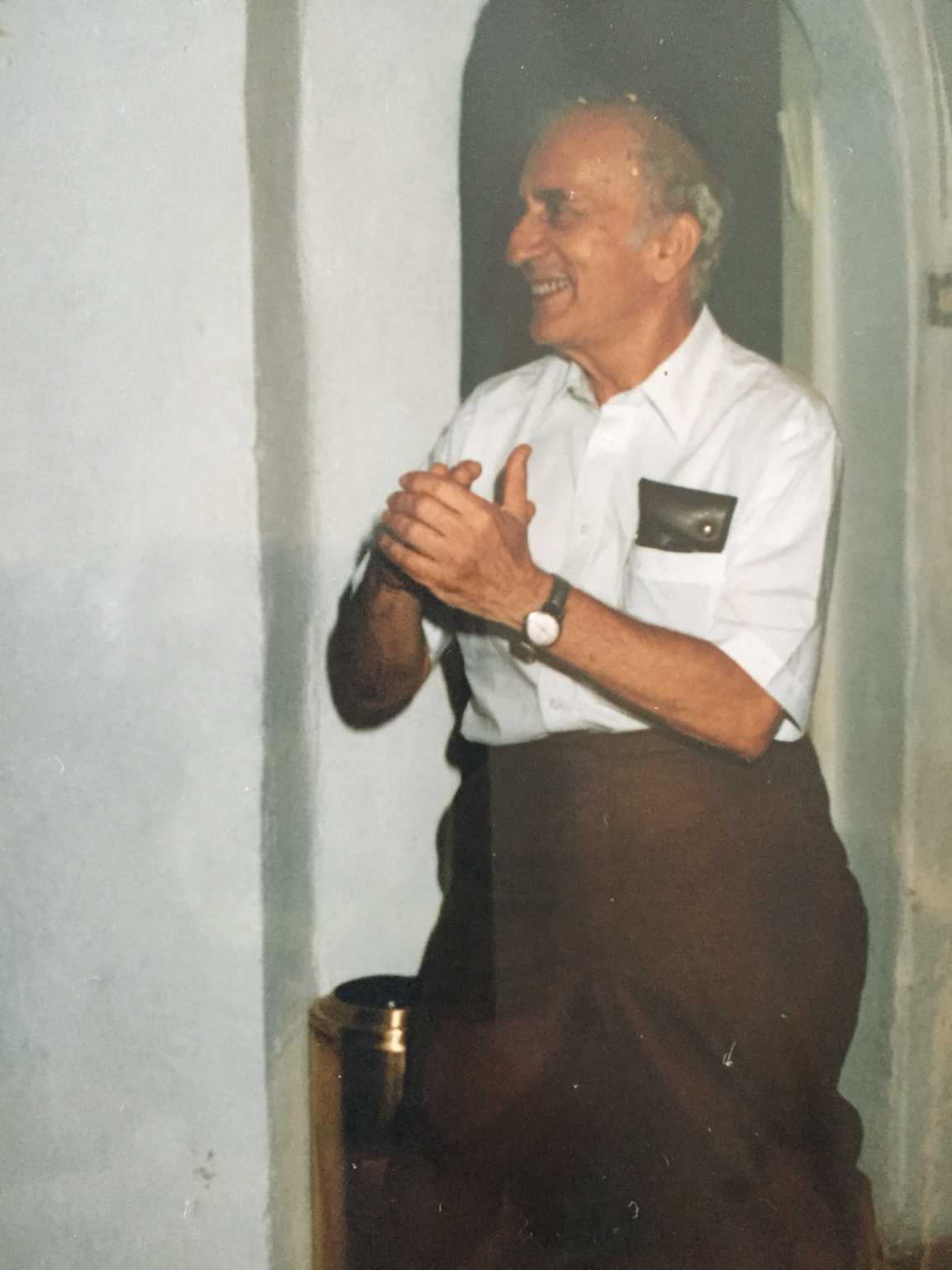 Leo Habel smiling in a white shirt with his hands clasped